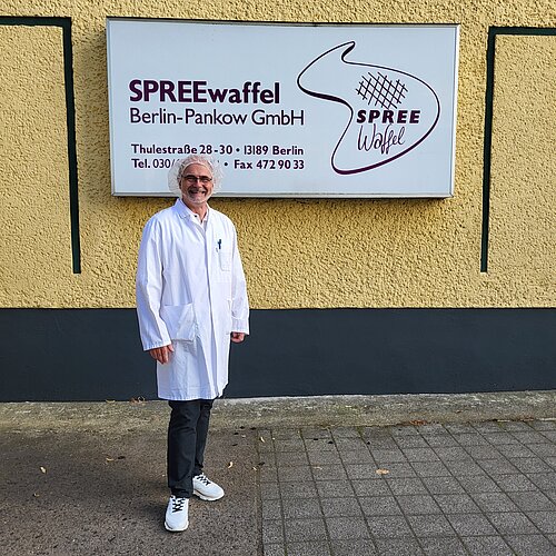 Betriebsleiter Stephan Küster steht vor dem SPREEwaffel-Firmenschild