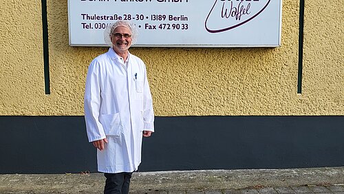 Betriebsleiter Stephan Küster steht vor dem SPREEwaffel-Firmenschild