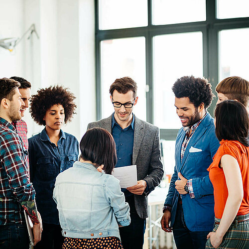Kolleg:innen stehen im Kreis und unterhalten sich angeregt. 