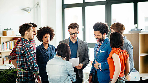 Kolleg:innen stehen im Kreis und unterhalten sich angeregt. 