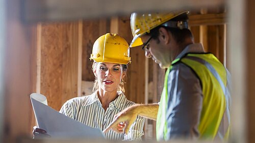 Arbeiter, die auf der Baustelle Pläne überprüfen.