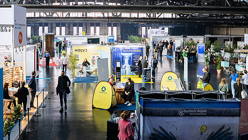 Blick in eine gefüllte Messehalle mit Ausstellern und Besuchern