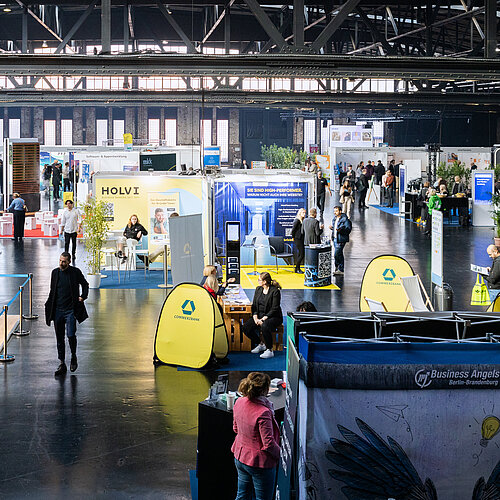 Blick in eine gefüllte Messehalle mit Ausstellern und Besuchern