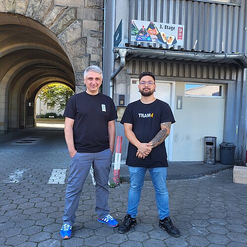 Zwei Mitarbeiter des Unternehmens RiCE UP onigiri stehen in einem Liefereingang.